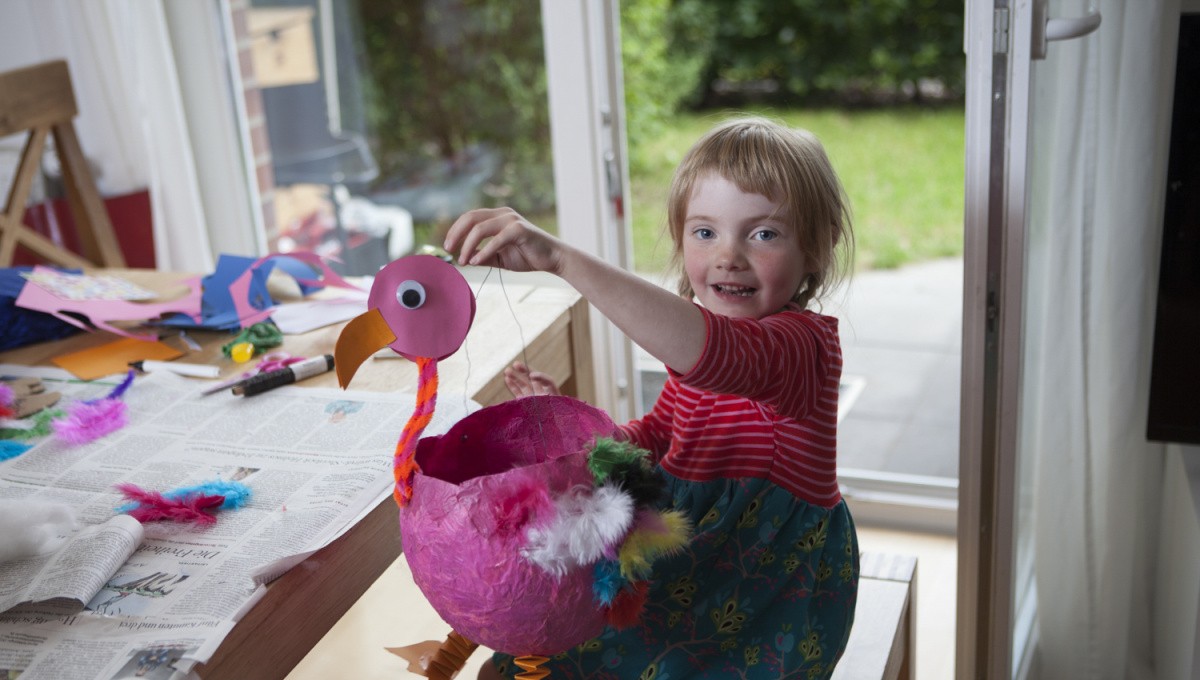 Mädchen hält selbstgebastelte Vogel-Laterne in die Höhe