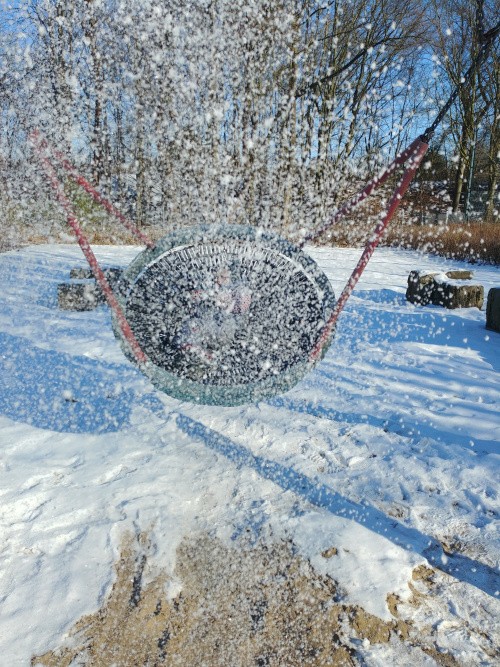 Kind schaukelt in Nestschaukel im Schnee