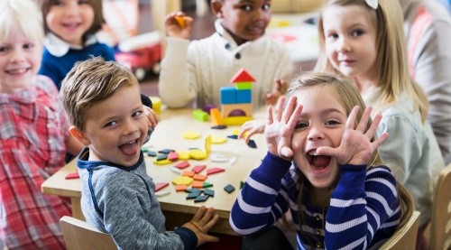 Fröhliche Kinder in der Kita mit Bauklötzen