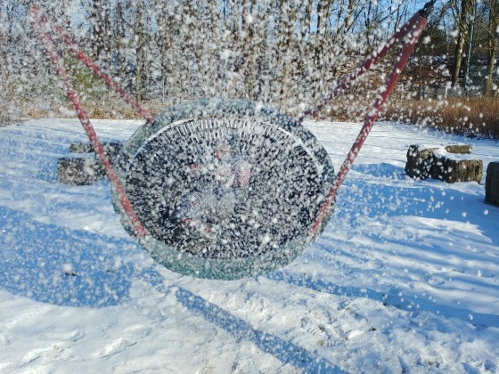 Kind schaukelt in Nestschaukel im Schnee