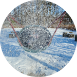 Kind schaukelt in Nestschaukel im Schnee Kind schaukelt in Nestschaukel im Schnee