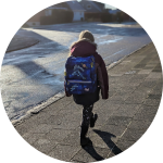 Kind mit Schulranzen auf dem Gehweg