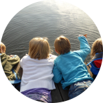 Vier Kinder liegen bäuchlings auf Steg am See Vier Kinder liegen bäuchlings auf Steg am See