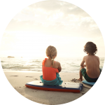 Zwei Kinder sitzen mit Bodyboards am Strand Zwei Kinder sitzen mit Bodyboards am Strand