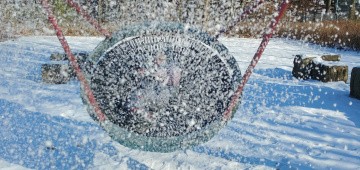 Kind schaukelt in Nestschaukel im Schnee