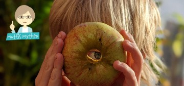 Kind hält sich entkernten Apfel vors Gesicht