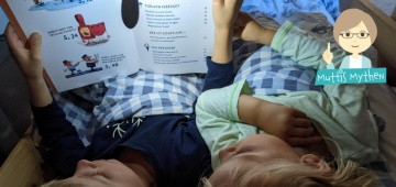 Kinder lesen mit Leselampe im Bett