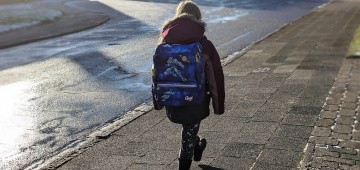 Kind mit Schulranzen auf dem Gehweg