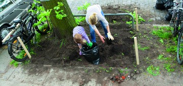 Frau und Kind bepflanzen Baumscheibe in der Stadt