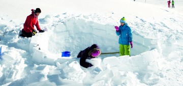 Kinder bauen Iglu vor Skipiste