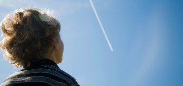 Junge schaut in den Himmel mit Kondensstreifen Junge schaut in den Himmel mit Kondensstreifen