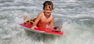 Junge hat Spaß in der Welle mit einem Bodyboard Junge hat Spaß in der Welle mit einem Bodyboard