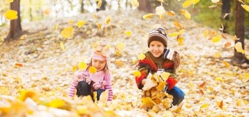 Zwei Kinder spielen mit Laub