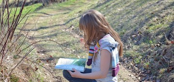 Kind mit Buch in der Natur