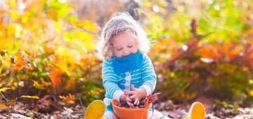 Ein Mädchen spielt mit Eicheln in einem Eimer