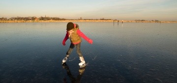 Kind fährt Schlittschuh auf See