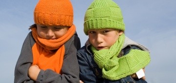 Zwei frierende Kinder mit bunten Mützen und Schals
