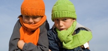 Zwei frierende Kinder mit bunten Mützen und Schals Zwei frierende Kinder mit bunten Mützen und Schals