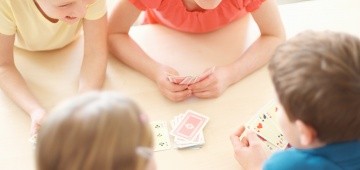 Kinder spielen Karten am Tisch Kinder spielen Karten am Tisch