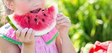 Mädchen beißt in Wassermelone Mädchen beißt in Wassermelone