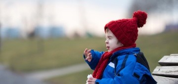 Ein Kind in Winterkleidung niest