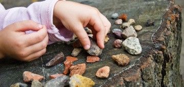 Kind sammelt Steine im Wald