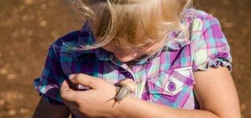 Mädchen mit Weinbergschnecke auf dem Arm