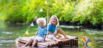 Kinder fahren mit einem Floß auf dem See Kinder fahren mit einem Floß auf dem See