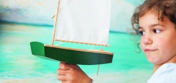 Ein Mädchen hält ein Segelschiff-Modell in der Hand