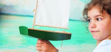 Ein Mädchen hält ein Segelschiff-Modell in der Hand Ein Mädchen hält ein Segelschiff-Modell in der Hand