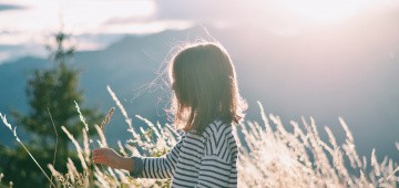 Kind auf Wiese im Gegenlicht der Sonne