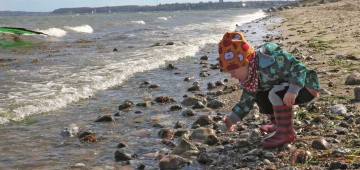 Kind sammelt Steine am Strand Kind sammelt Steine am Strand