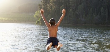 Ein Kind springt in einen See