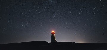 Nachthimmel mit Leuchtturm und Sternschnuppen