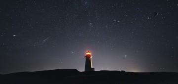 Nachthimmel mit Leuchtturm und Sternschnuppen