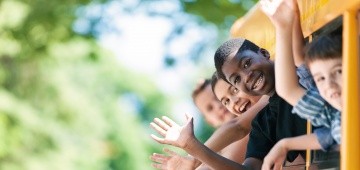 Vier Kinder winken aus einem Zugfenster