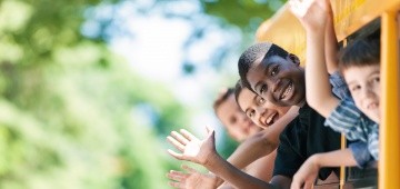 Vier Kinder winken aus einem Zugfenster