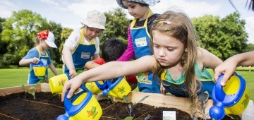 Kinder gießen Pflanzen im Hochbeet