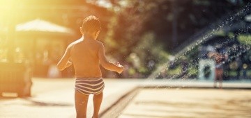 Junge spielt in Springbrunnen im Sommer Junge spielt in Springbrunnen im Sommer
