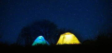 Zwei beleuchtete Zelte unter Sternenhimmel
